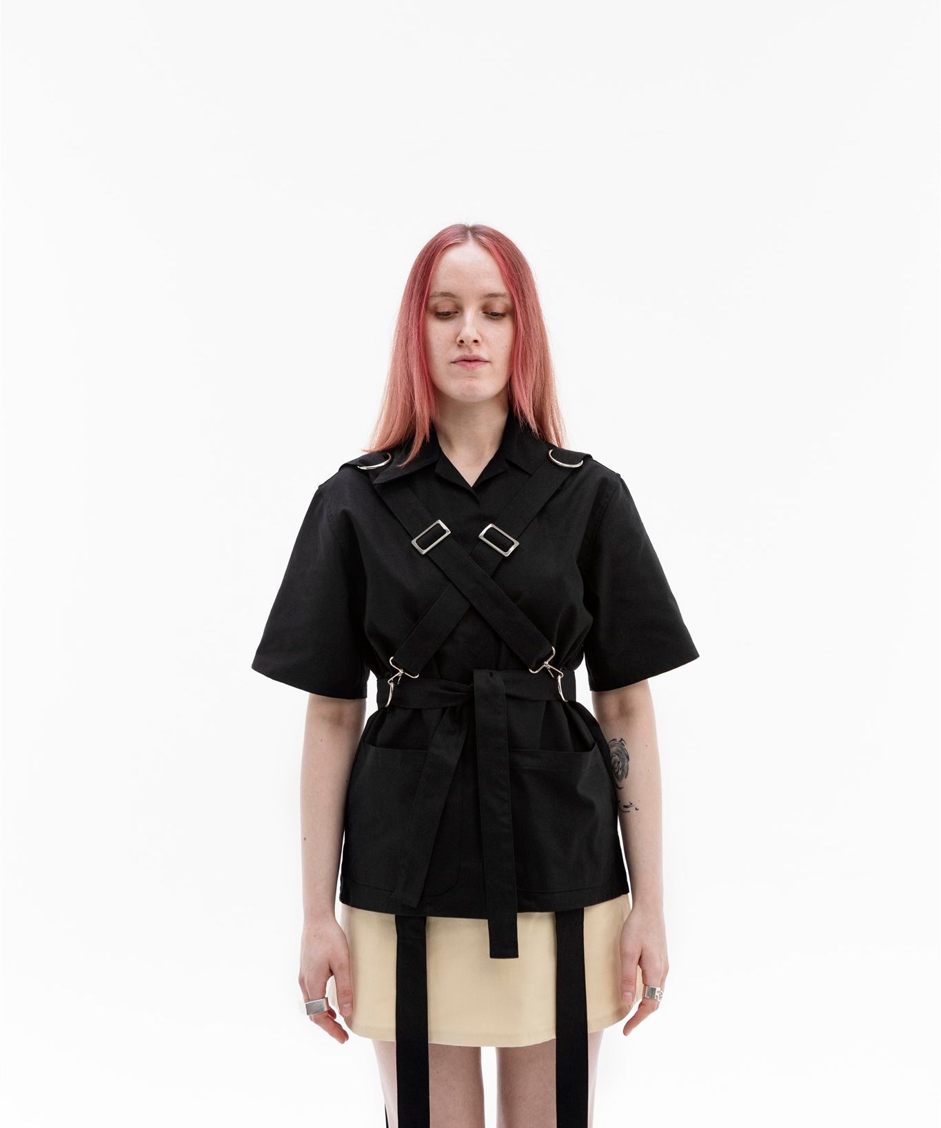 Front view of the Emily Millichip Bondage Shirt in black cotton canvas, showing cross straps, stainless steel buckles, oversized patch pockets and a waist belt.