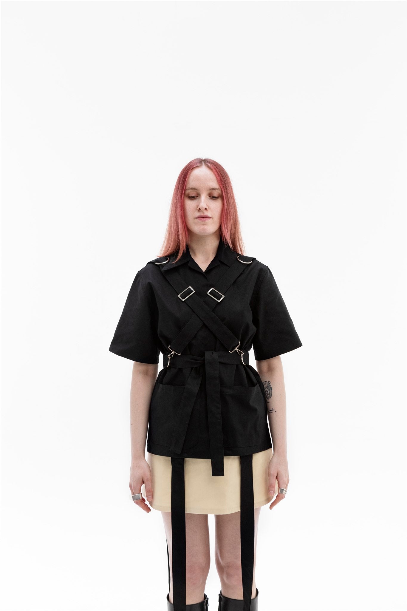 Front view of the Emily Millichip Bondage Shirt in black cotton canvas, showing cross straps, stainless steel buckles, oversized patch pockets and a waist belt.