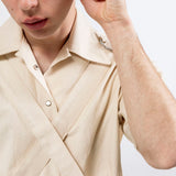 Close up of the natural seeded cotton canvas Bondage Shirt by Emily Millichip, showing the camp collar, crossed canvas straps, and stainless steel buckles.