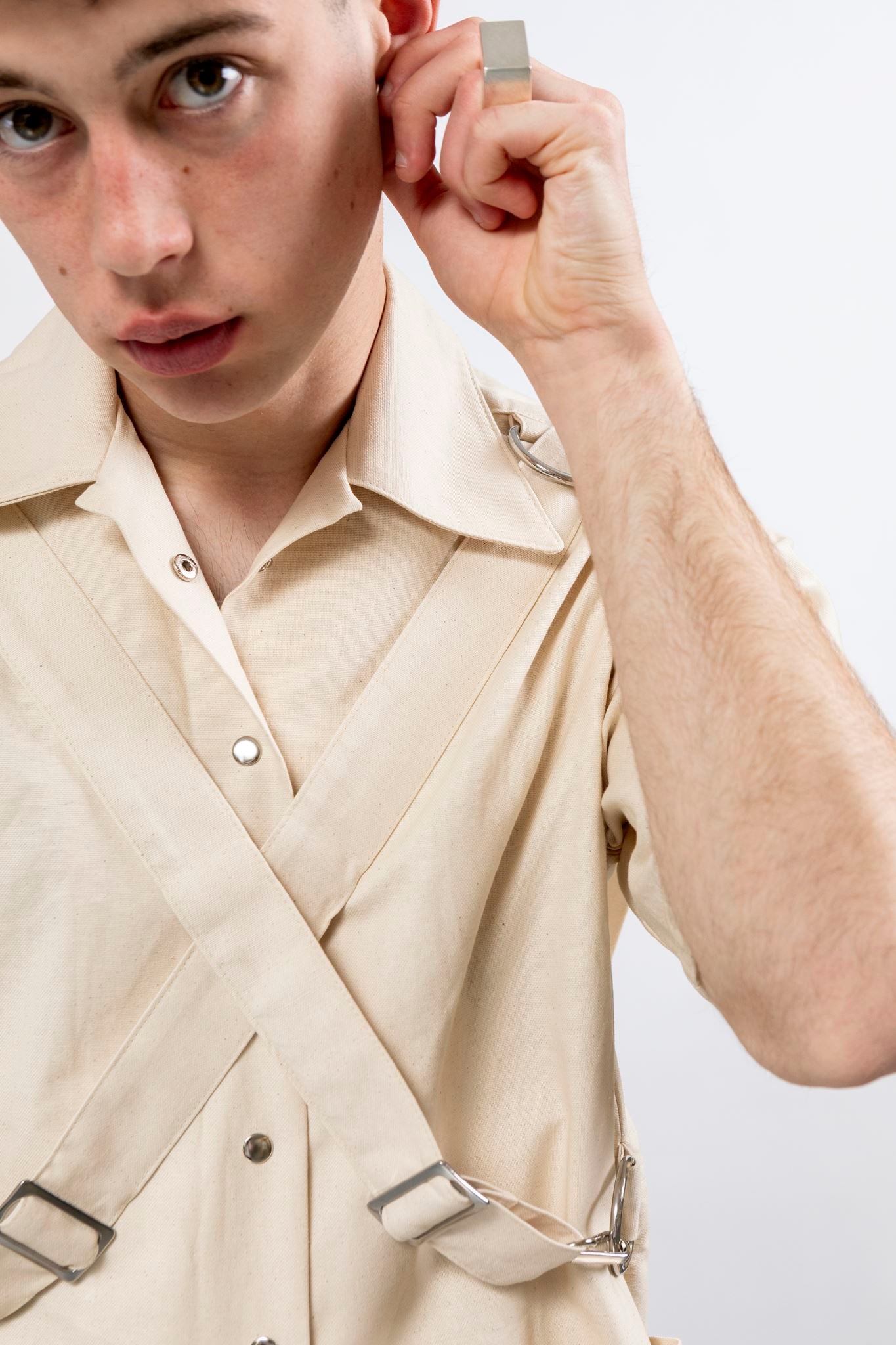 Close up of the natural seeded cotton canvas Bondage Shirt by Emily Millichip, showing the camp collar, crossed canvas straps, and stainless steel buckles.