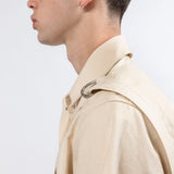 Side profile of the Emily Millichip Bondage Shirt in natural seeded cotton canvas, showing the camp collar, shouder strap, and stainless steel d-ring detail.