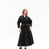Full-length studio photograph of a model wearing the Emily Millichip Gravity Field Jacket in black heavyweight sanded canvas, styled with matching long black skirt and boots against a white background.